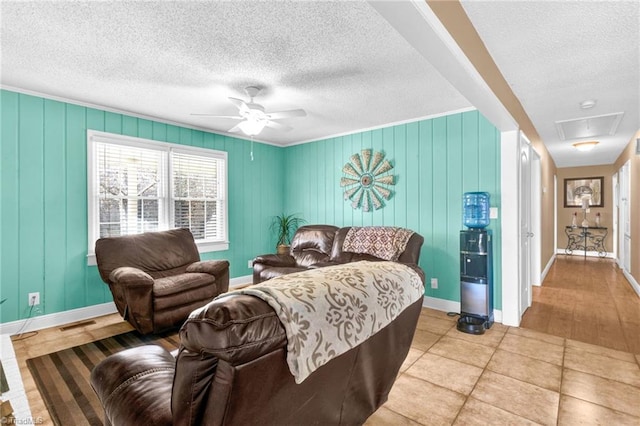 living room featuring ceiling fan, crown molding, light tile patterned floors, and a textured ceiling