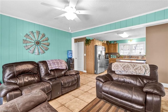 living room featuring sink, crown molding, ceiling fan, a textured ceiling, and light tile patterned flooring