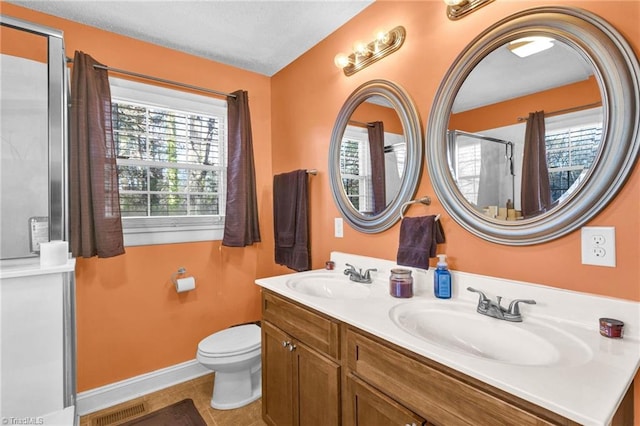 bathroom with tile patterned floors, vanity, toilet, and walk in shower