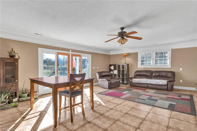 tiled living room featuring a textured ceiling, ceiling fan, crown molding, and french doors