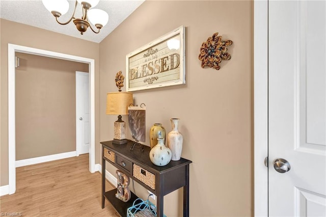 entryway featuring a textured ceiling, light wood-type flooring, and a notable chandelier