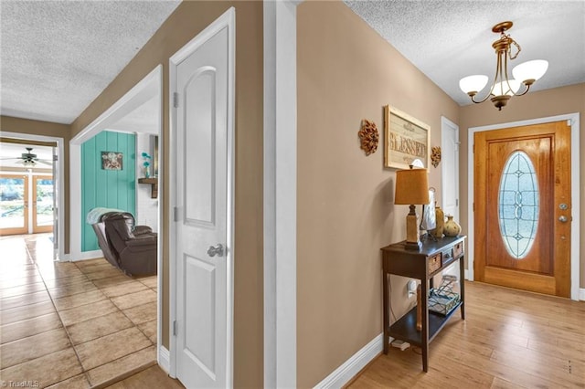 entryway featuring a textured ceiling, ceiling fan with notable chandelier, and light hardwood / wood-style floors