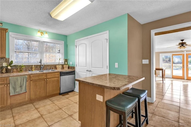 kitchen featuring stainless steel dishwasher, plenty of natural light, sink, and a breakfast bar