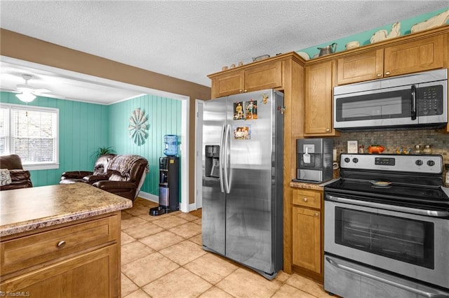 kitchen with decorative backsplash, ceiling fan, light tile patterned floors, a textured ceiling, and stainless steel appliances