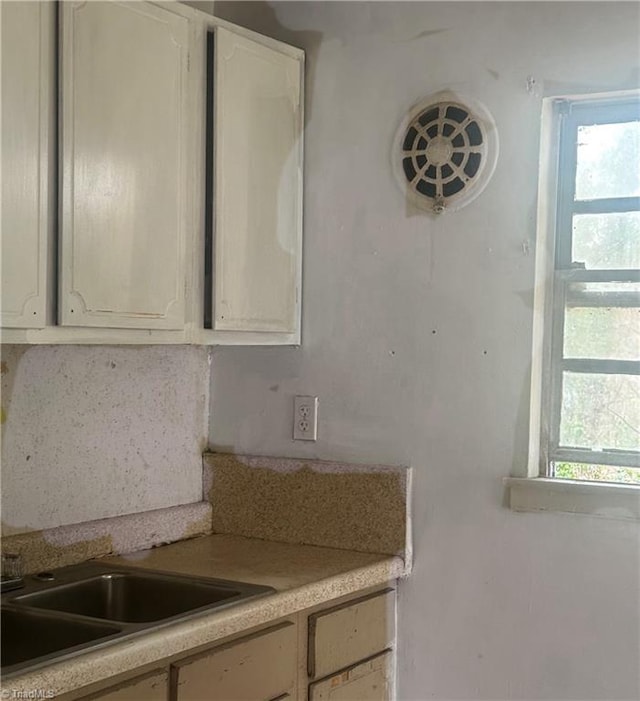 kitchen with light countertops, white cabinets, a healthy amount of sunlight, and a sink