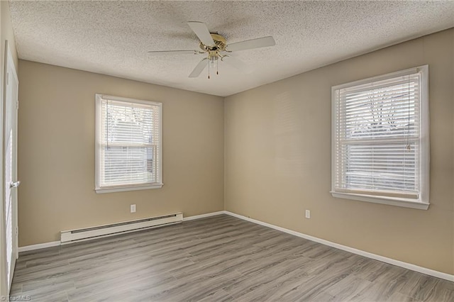 unfurnished room featuring a textured ceiling, plenty of natural light, light hardwood / wood-style flooring, and a baseboard heating unit