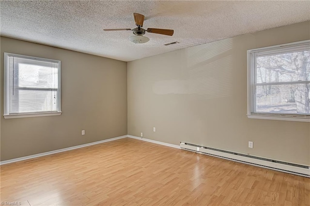 spare room featuring light wood-type flooring, a textured ceiling, and a baseboard heating unit