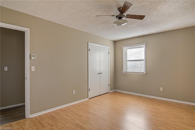 unfurnished bedroom with ceiling fan, light wood-type flooring, a textured ceiling, and a closet