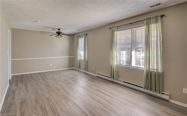 empty room featuring light hardwood / wood-style floors, baseboard heating, and a healthy amount of sunlight