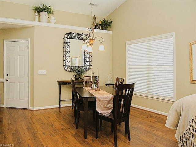 dining room with lofted ceiling, wood finished floors, baseboards, and visible vents