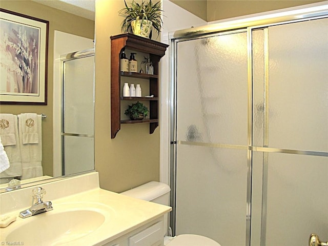 full bathroom with toilet, vanity, and a shower with shower door