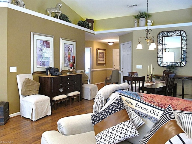 bedroom featuring visible vents, baseboards, lofted ceiling, wood finished floors, and a notable chandelier