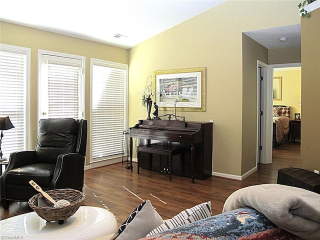 living room with vaulted ceiling, baseboards, visible vents, and wood finished floors