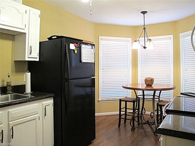 kitchen featuring dark wood-style floors, dark countertops, white cabinets, and freestanding refrigerator