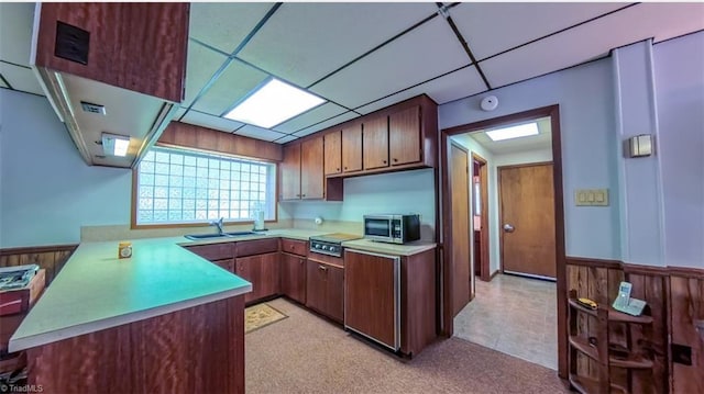 235 Hogan Bowers Rd, Thomasville, NC 27360 - kitchen featuring light countertops, a wainscoted wall, a peninsula, stainless steel microwave, and a sink