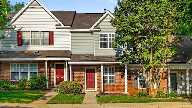 view of property featuring a shingled roof and brick siding