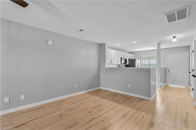 kitchen featuring visible vents, refrigerator, baseboards, white cabinetry, and light wood-style flooring
