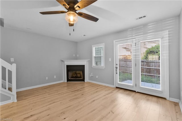 unfurnished living room featuring light wood finished floors, a fireplace, a ceiling fan, baseboards, and visible vents