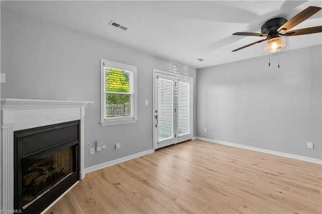 unfurnished living room featuring ceiling fan, light wood-style floors, a fireplace, baseboards, and visible vents