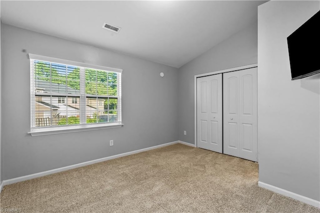 unfurnished bedroom featuring visible vents, carpet, baseboards, and vaulted ceiling