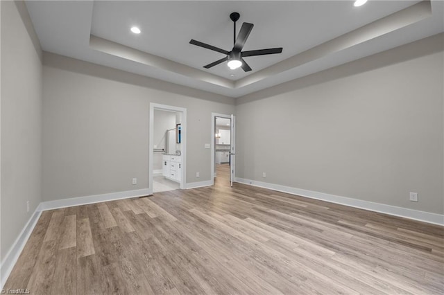 spare room with a tray ceiling, light wood finished floors, a ceiling fan, and recessed lighting