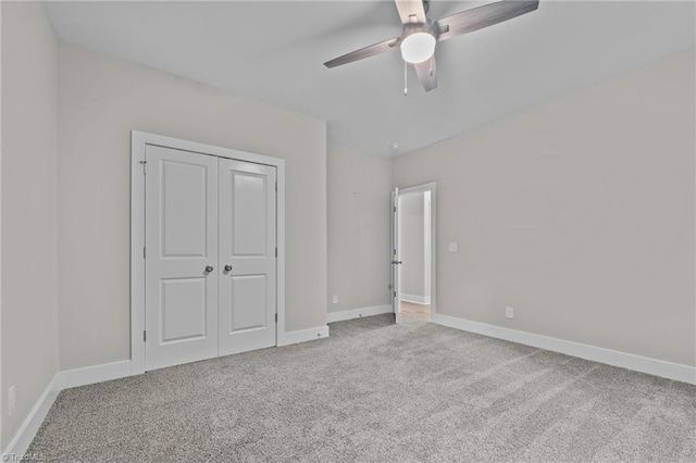 unfurnished bedroom featuring carpet flooring, baseboards, a closet, and a ceiling fan