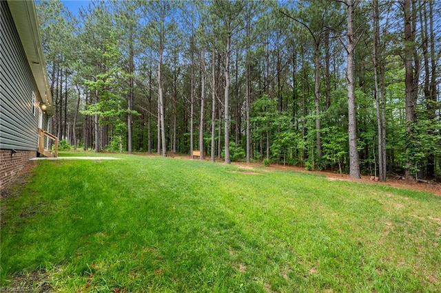 view of grassy yard featuring a view of trees