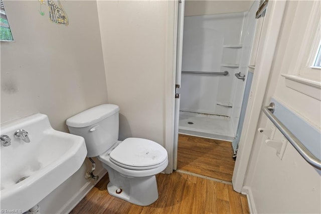 bathroom featuring a sink, walk in shower, toilet, and wood finished floors