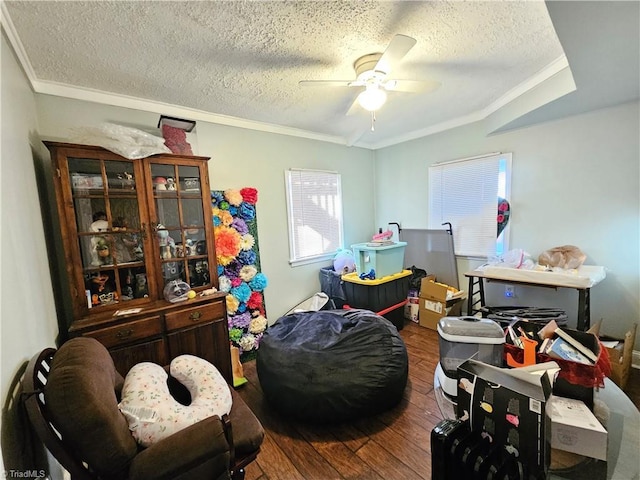 game room with ceiling fan, a textured ceiling, wood-type flooring, and ornamental molding