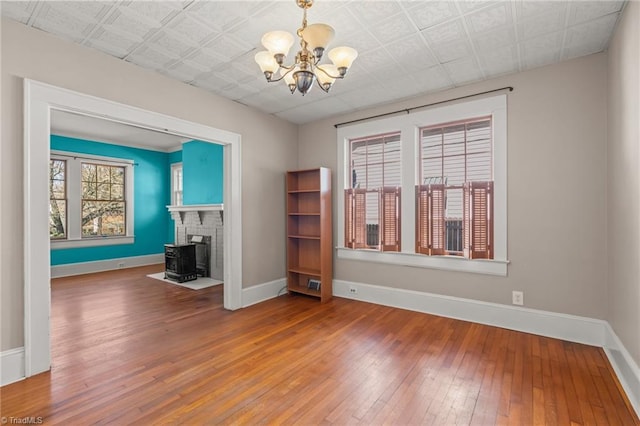 unfurnished living room with hardwood / wood-style flooring, a chandelier, and a fireplace