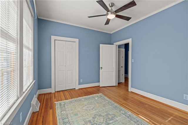 unfurnished bedroom featuring a closet, ceiling fan, crown molding, and hardwood / wood-style flooring