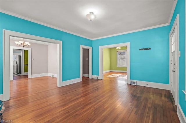 spare room with dark hardwood / wood-style flooring, ornamental molding, and a chandelier