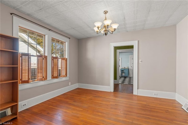 spare room with hardwood / wood-style floors and a notable chandelier