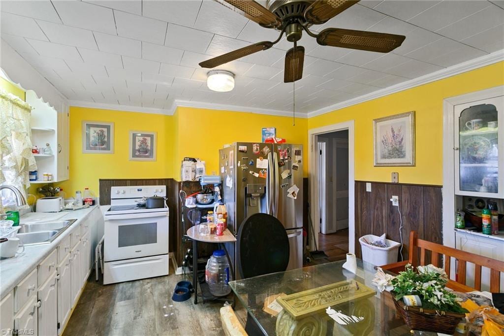 kitchen with white electric range oven, a sink, white cabinets, stainless steel refrigerator with ice dispenser, and crown molding