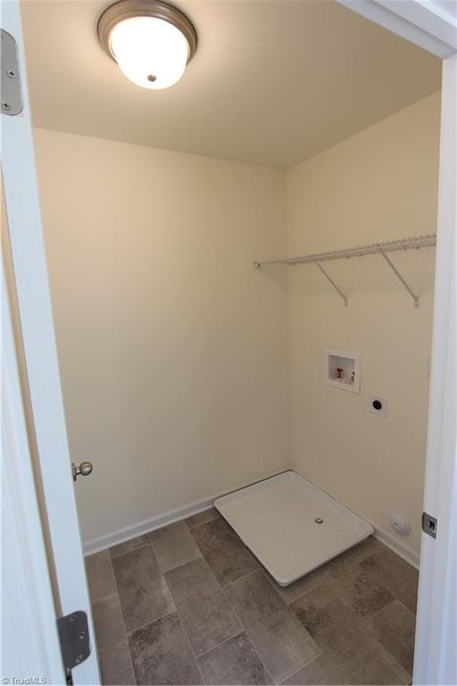 clothes washing area with dark tile patterned flooring, hookup for a washing machine, and hookup for an electric dryer