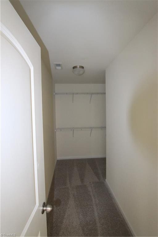 walk in closet featuring dark carpet