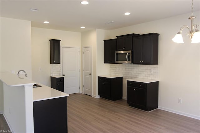 kitchen with decorative backsplash, hardwood / wood-style floors, an inviting chandelier, sink, and hanging light fixtures