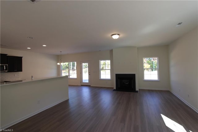 unfurnished living room featuring plenty of natural light and dark hardwood / wood-style flooring