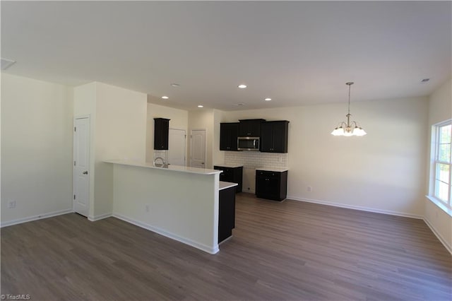 kitchen featuring decorative backsplash, pendant lighting, hardwood / wood-style floors, and a chandelier