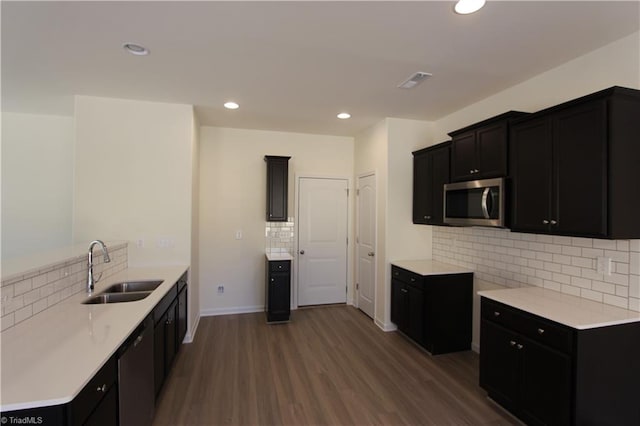 kitchen with sink, decorative backsplash, hardwood / wood-style floors, and dishwashing machine