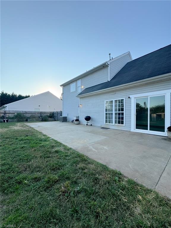 back of property with central AC unit, a yard, and a patio