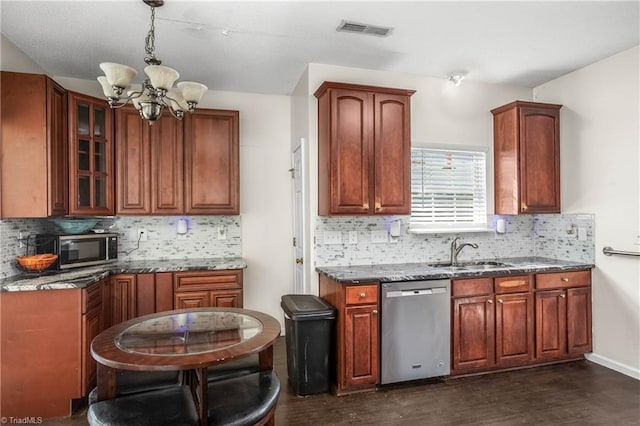 kitchen featuring appliances with stainless steel finishes, tasteful backsplash, dark wood-type flooring, decorative light fixtures, and a notable chandelier