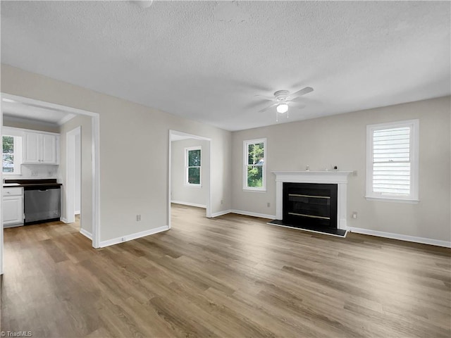 unfurnished living room featuring ceiling fan, hardwood / wood-style floors, a textured ceiling, and plenty of natural light