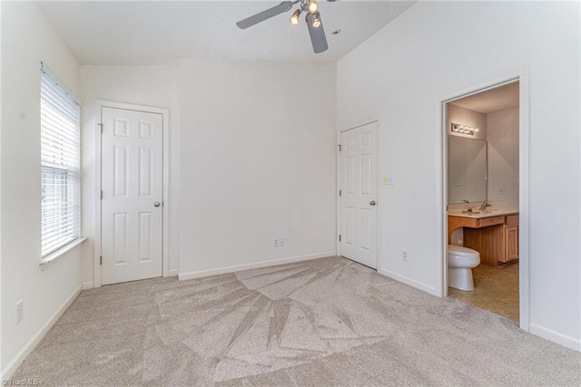 unfurnished bedroom with baseboards, carpet, ensuite bathroom, and vaulted ceiling