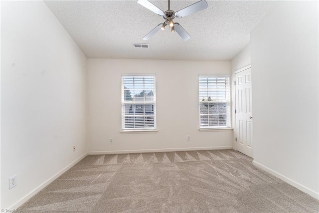 carpeted spare room with ceiling fan, baseboards, visible vents, and a textured ceiling