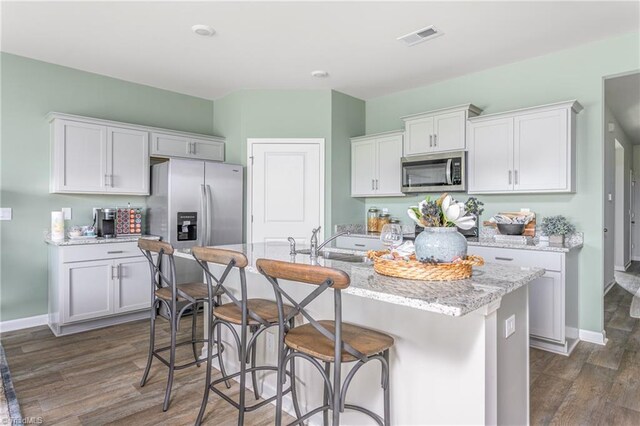 kitchen with white cabinetry, a kitchen island with sink, dark hardwood / wood-style flooring, and stainless steel appliances