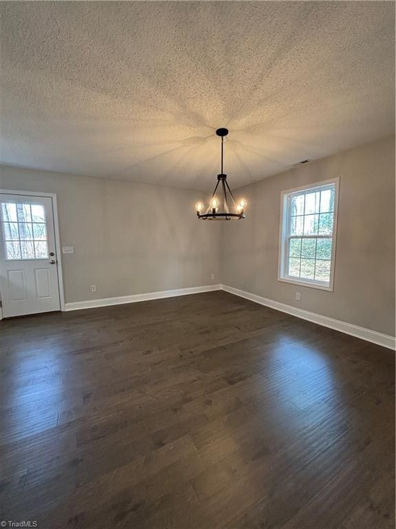 unfurnished dining area featuring dark wood-style floors, a chandelier, plenty of natural light, and baseboards