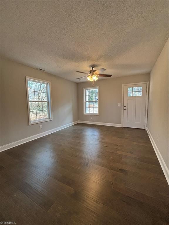 interior space with visible vents, baseboards, dark wood finished floors, and a ceiling fan