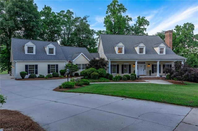 new england style home featuring a front yard and covered porch