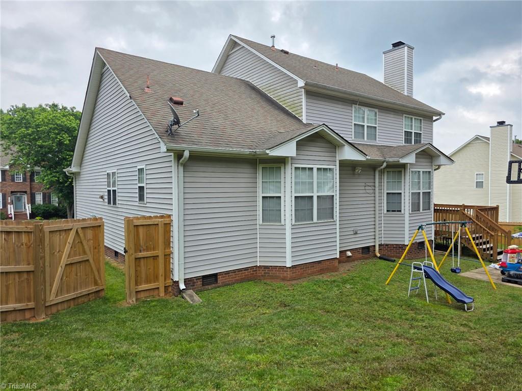 4803 Tenby Dr, Greensboro, NC 27455 - back of property featuring crawl space, a playground, and a shingled roof